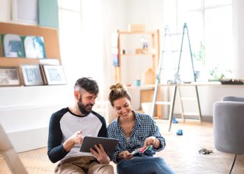Mid adults couple planning with tablet indoors at home, relocation and diy concept.